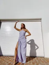 Vestido largo color naranja, con escote halter cruzado y falda tipo pareo con tajo lateral. Confeccionado en tela crepé con caída fluida.