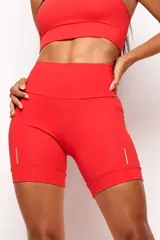 Short biker deportivo de tiro alto, color rojo, con bolsillos laterales y detalles reflectivos en las piernas. Confeccionado en tejido técnico de alta performance con cintura anatómica.