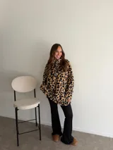 Buzo de peluche con estampado animal print en blanco y negro, cuello alto y cierre frontal con tirador personalizado.