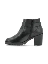 Botin de cuero graneado negro con taco cuadrado y suela track. Presenta una tira con tachas y una argolla metálica decorativa alrededor del tobillo.
