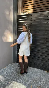 Vestido corto color crudo, con escote en V y mangas 3/4 abullonadas con detalles de calado.