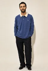 Buzo de manga larga estilo rugby color azul petróleo, con cuello beige en contraste, tapeta con botones y pequeño bordado en el pecho. Confeccionado en algodón pesado con fit relajado.