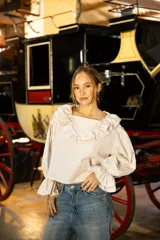 Blusa de algodón con estampado a cuadros vichy en tonos beige y blanco. Presenta un diseño con volados en el escote, mangas largas amplias y puños con volados.