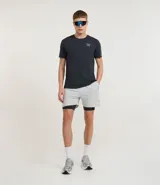 Short deportivo para hombre, color gris claro, con short de compresión negro incorporado. Presenta un pequeño logo bordado en la pierna derecha.