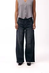 Jean wide leg de tiro medio confeccionado en denim azul oscuro, con costuras visibles que aportan estructura y diseño vertical.