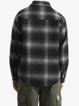 Camisa tipo sobrecamisa Carhartt de corte holgado, confeccionada en tejido de lana a cuadros en tonos negro y gris. Presenta cierre frontal de botones a presión, cuello clásico, mangas largas con puños abotonados y un bolsillo en el pecho con etiqueta de la marca.