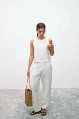 Bolso tipo tote tejido con tiras de plástico de colores amarillo, morado, naranja y negro.