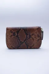 Billetera pequeña de cuero color marrón con estampado de piel de serpiente, cierre exterior, bolsillo trasero para monedas con cierre, múltiples ranuras para tarjetas y billetes, y forro rojo.