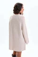 Buzo de tejido de punto en color crudo, con diseño de textura acanalada, cuello redondo, mangas largas holgadas y aberturas laterales en el ruedo.