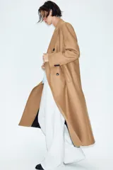 Abrigo largo negro ZARA Woman Collection de corte recto, confeccionado con hilatura de lana. Presenta cuello con solapa de muesca, cierre cruzado de doble botonadura frontal y bolsillos ribeteados en los laterales.