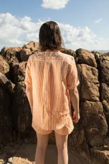 Camisa de manga corta oversize en lino rayado, con cuello camisero, cierre frontal con botones y bordado playero en el frente.