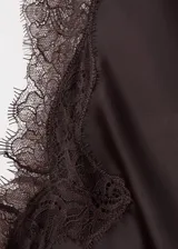 Vestido midi asimétrico de satén marrón oscuro, de corte recto y sin mangas, con detalles de encaje en el escote y en el ruedo.