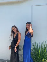 Vestido largo con escote en V, estampado en tonos rojizos y rosados, con un patrón ondulado. Presenta cut-outs laterales bajo el busto y breteles finos que se cruzan en la espalda.