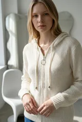 Sweater tipo campera de tejido de punto acanalado en color crudo, con cierre frontal completo, capucha con cordones ajustables y puños y ruedo tejidos en rib.