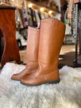 Botas altas de cuero en color tostado, de caña alta y diseño clásico con tirador superior.