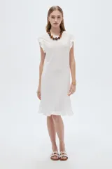 Vestido midi de poliéster color blanco, de corte recto y escote redondo a la base, con mangas cortas abuchonadas con volados y detalles de volados en el ruedo.