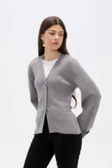 Saco de punto gris con cuello en V, cierre frontal con botones y mangas largas con puños anchos decorados con botones.