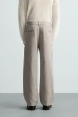 Pantalón de vestir color blanco hueso, de corte recto y tiro medio, con cintura elástica y cierre frontal de botón y cremallera. Presenta bolsillos frontales y bolsillos traseros de vivo.