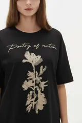 Remera blanca de algodón de manga corta, con cuello redondo y corte holgado. Presenta estampado frontal de un lazo con detalles de brillos y la frase 'Made of sweetness'.