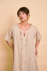 Vestido tipo túnica largo de lino color beige, de manga corta, con detalles de volados en el frente y bolsillos laterales.