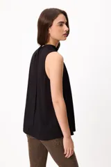 Blusa sin mangas color crema, con cuello alto fruncido y diseño holgado.