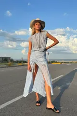 Conjunto de dos piezas en color celeste, confeccionado en tela de gasa con textura arrugada. Incluye un top sin mangas de cuello redondo y una falda midi con ajuste de frunce delantero que permite regular la altura del tajo.