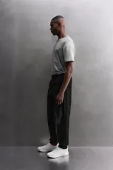 Pantalón jogger negro de corte regular, confeccionado en tejido técnico con algodón. Presenta cintura elástica ajustable con cordón interior, bolsillos laterales y puños elásticos en los tobillos. Posee un pequeño logo estampado en contraste en la pierna derecha.