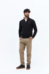 Sweater de tejido liso color verde oscuro, con cuello medio y cierre frontal parcial plateado. Presenta puños y cintura acanalados, y un pequeño logo bordado en el pecho.