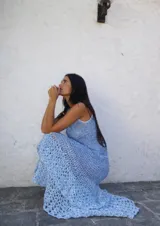 Vestido largo de crochet en color azul marino, con diseño sin mangas y cuello redondo. Presenta un detalle de apliques metálicos en la zona del pecho y un ruedo con volado de textura contrastante.