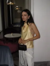 Top de satén color amarillo pastel, con diseño de cuello halter y espalda descubierta. Presenta una caída fluida y elegante, con un corte minimalista que se ajusta suavemente al cuerpo.
