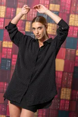 Camisa negra con pequeños apliques brillantes, corte oversize y mangas largas.