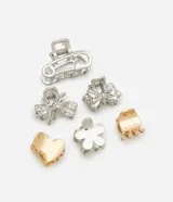 Set de seis pinzas pequeñas para el pelo, con diseños variados: una con forma de gancho de seguridad, dos con forma de moño, una con forma de flor, una con forma de corazón y una rectangular. Los colores son plateado y dorado.