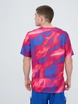 Remera de entrenamiento Umbro del Club Nacional de Football, modelo Press, para hombre. Diseño en tonos de rojo con patrón estampado tipo humo o abstracto, cuello redondo y mangas cortas. Incluye el logo de Umbro y el escudo del club en el pecho.