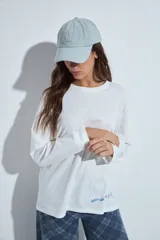 Remera de manga larga en color blanco, con corte relajado y cuello redondo. Presenta un pequeño estampado gráfico en la parte inferior frontal con la frase 'WHO WH WHO?' y un dibujo de un perro.