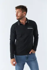 Polo de manga larga negra con cuello clásico, tapeta de dos botones y bolsillo de parche en el pecho con ribete blanco. Logo de la marca bordado en blanco sobre el bolsillo.
