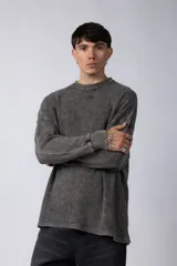 Buzo de corte oversize confeccionado en tela waffle de algodón con proceso de teñido acid wash. Presenta cuello redondo con detalle de costura en X y mangas largas con puños acanalados.