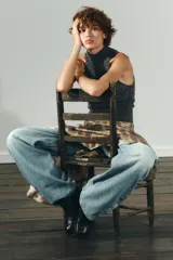 Top de punto jaspeado en color gris oscuro, con cuello alto y diseño halter sin mangas. Confeccionado con una mezcla que incluye lana, presenta terminaciones acanaladas en el cuello y el ruedo.