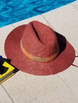 Sombrero de paja color ladrillo con cinta tejida en tonos ocre y amarillo.