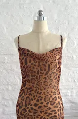 Vestido largo ajustado de microtul elastizado, con estampado de leopardo en tonos marrón y negro. Presenta escote drapeado tipo cowl neck y tirantes finos ajustables.