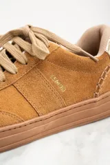 Zapatillas bajas color marrón claro, confeccionadas en gamuza con detalles en cuero dorado en el talón.
