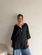 Blusa de viscosa color negro, de corte holgado y diseño largo, con escote en V y detalle de botón central.