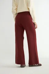 Pantalón de punto color crema, de corte recto y holgado, con cintura elástica y cordón ajustable. Presenta costuras verticales decorativas a lo largo de las piernas.