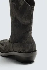 Bota estilo cowboy fabricada en tejido denim de algodón con efecto lavado, diseño de caña media con tiradores laterales, horma cuadrada y tacón ancho.