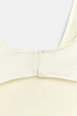 Vestido corto satinado de color blanco marfil, con escote redondo, tirantes finos y aberturas laterales tipo cut out.