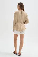 Blusa de poliéster color negro con cuello alto, mangas largas, diseño holgado, detalles de frunces y lazo ajustable en la cintura.