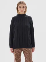 Buzo tejido de punto color beige, con cuello subido, diseño oversized y aberturas laterales en el ruedo.