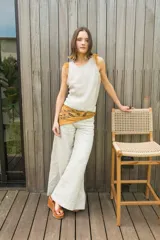 Chaleco color crema de tejido de punto calado, con cuello redondo y detalle de plumas en los hombros.