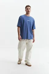 Remera azul de manga corta con corte oversize y cuello redondo. Estampado en la espalda con la frase "Cookies & Milk" y dibujos de una galleta y un cartón de leche.