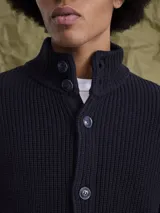 Sweater de punto grueso color azul marino, con cuello alto y cierre frontal de botones.