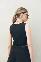 Chaleco crop top negro de denim con ajuste frontal con cordones.